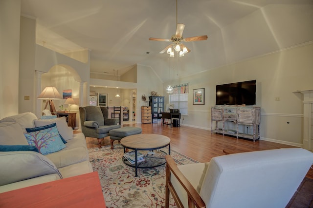 living room featuring high vaulted ceiling, a ceiling fan, wood finished floors, arched walkways, and ornate columns