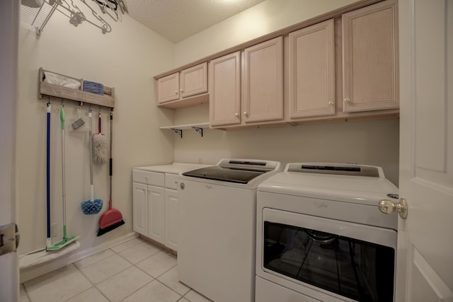 washroom featuring cabinet space, a textured ceiling, washing machine and dryer, and light tile patterned flooring