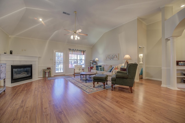 living room with visible vents, wood finished floors, crown molding, a fireplace, and ornate columns