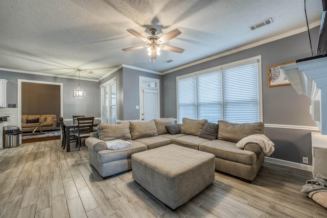 living area with ornamental molding, visible vents, and wood tiled floor