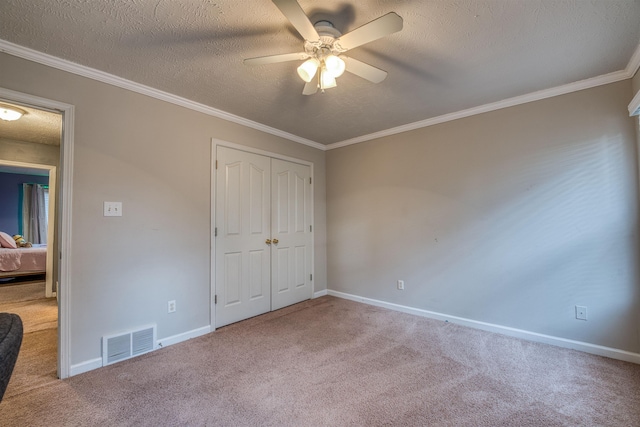 unfurnished bedroom featuring visible vents, carpet flooring, a textured ceiling, and ornamental molding