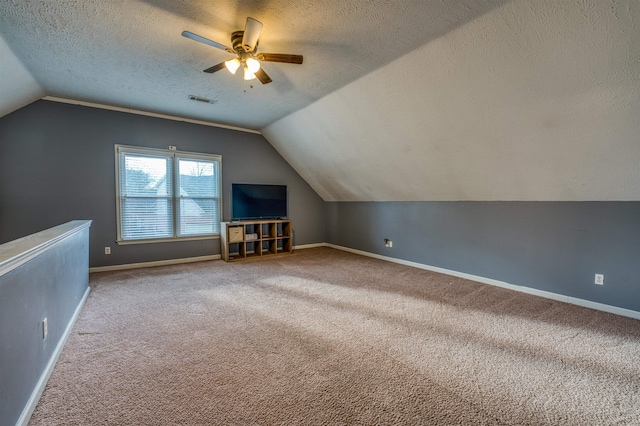 additional living space featuring visible vents, baseboards, vaulted ceiling, carpet floors, and a textured ceiling