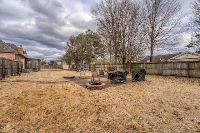 view of yard with a playground, a fenced backyard, and an outdoor fire pit