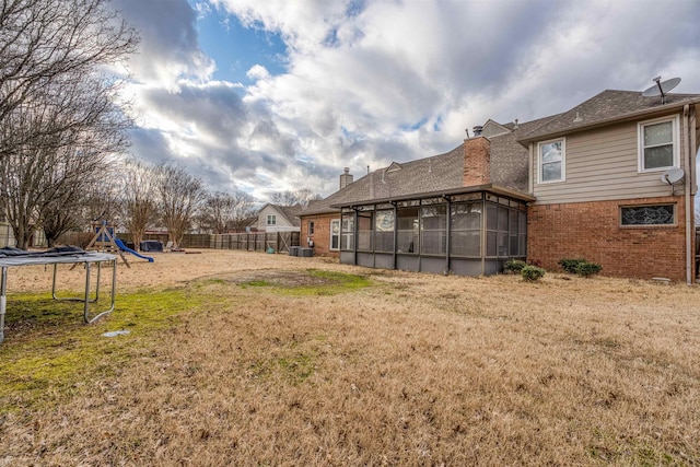 view of yard featuring central AC unit, a playground, fence, and a sunroom