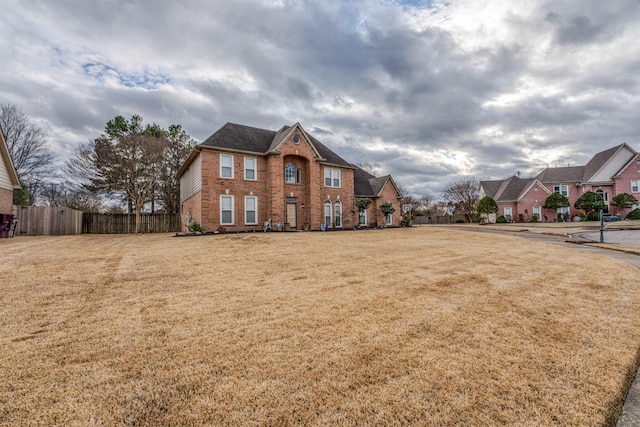 view of front of property with a front yard, fence, and brick siding