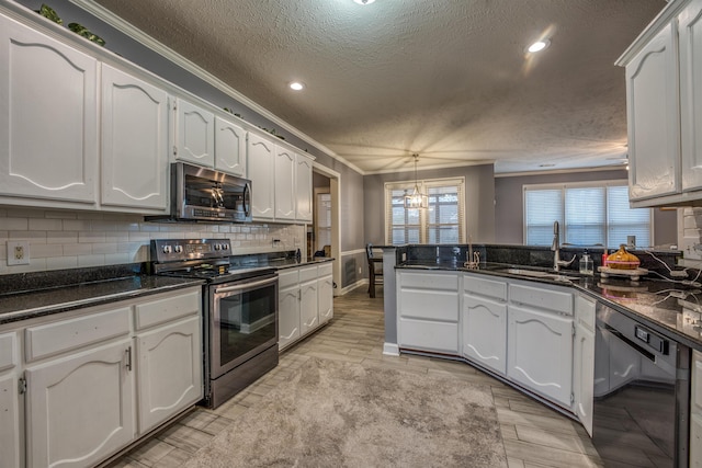 kitchen featuring tasteful backsplash, ornamental molding, white cabinets, stainless steel appliances, and a sink