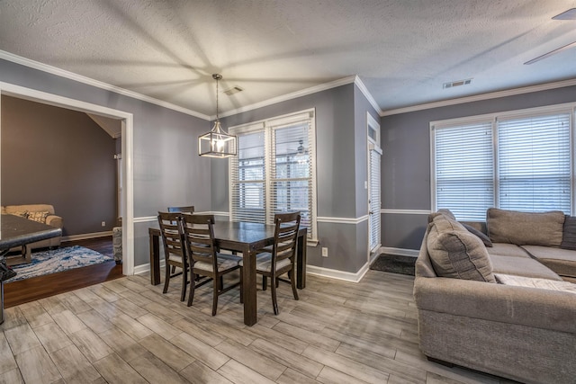 dining room with visible vents, plenty of natural light, a textured ceiling, and wood finished floors