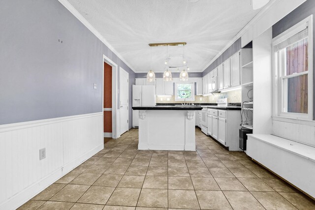 kitchen with white appliances, ornamental molding, white cabinets, wainscoting, and a center island