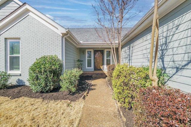 entrance to property with brick siding and a shingled roof