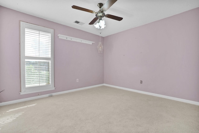 carpeted spare room featuring visible vents, baseboards, and a ceiling fan