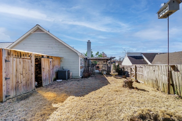 view of yard with central AC and fence