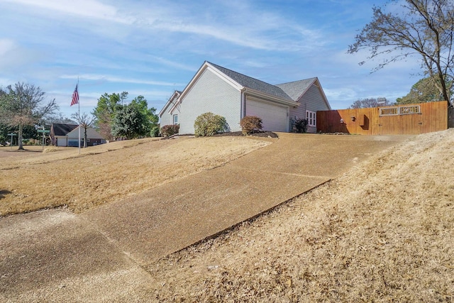 view of home's exterior with a garage, concrete driveway, and fence