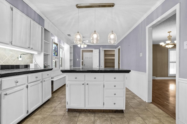 kitchen with white cabinetry, dark countertops, light tile patterned flooring, and a wainscoted wall