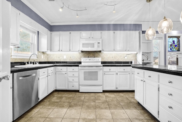 kitchen featuring dark countertops, white cabinets, white appliances, and a sink