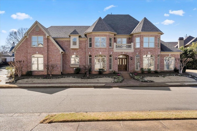 view of front of property featuring brick siding and roof with shingles