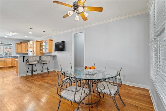 dining space featuring light wood finished floors, baseboards, and ornamental molding