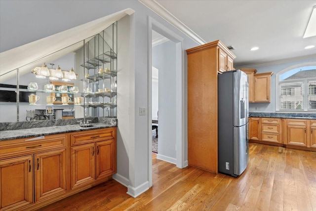 kitchen with crown molding, light wood-style flooring, stainless steel fridge with ice dispenser, and a sink