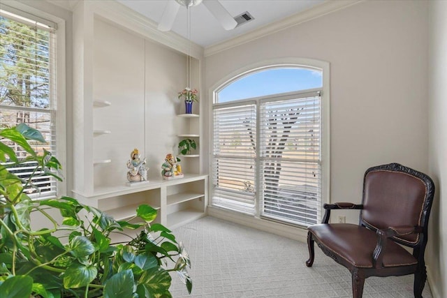 sitting room featuring ceiling fan, carpet flooring, visible vents, and ornamental molding