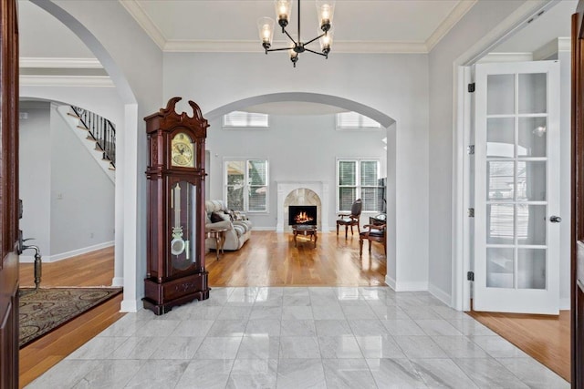 entrance foyer with crown molding, baseboards, light wood finished floors, and a premium fireplace