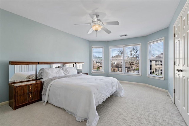 bedroom featuring light colored carpet, multiple windows, baseboards, and visible vents