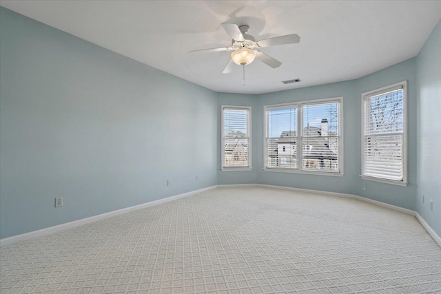 empty room featuring light carpet, visible vents, ceiling fan, and baseboards