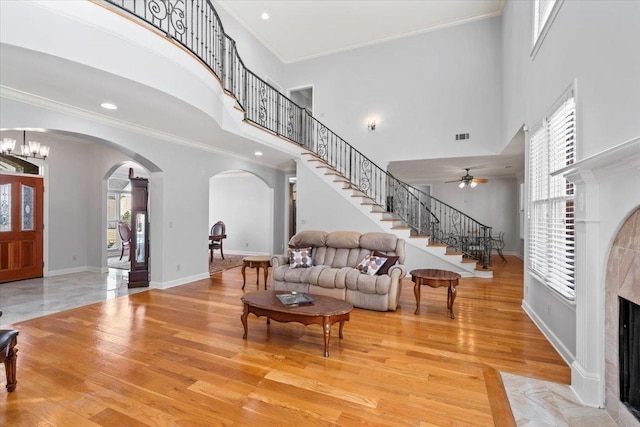 living room featuring stairway, a tile fireplace, light wood-type flooring, and ornamental molding