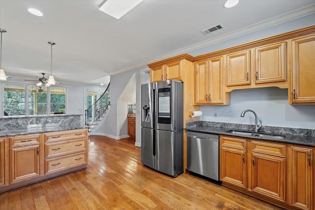 kitchen featuring visible vents, light wood-type flooring, ornamental molding, appliances with stainless steel finishes, and a sink