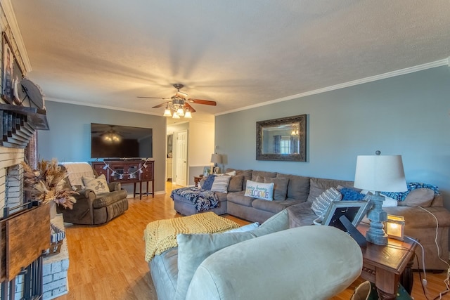 living room with a fireplace, a ceiling fan, wood finished floors, and crown molding