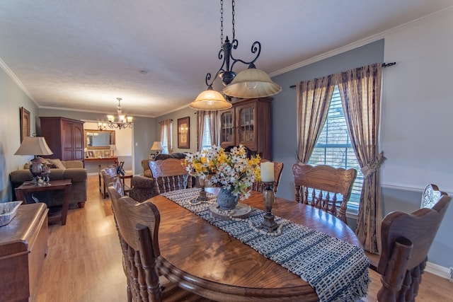 dining area featuring a notable chandelier, light wood-style flooring, crown molding, and baseboards