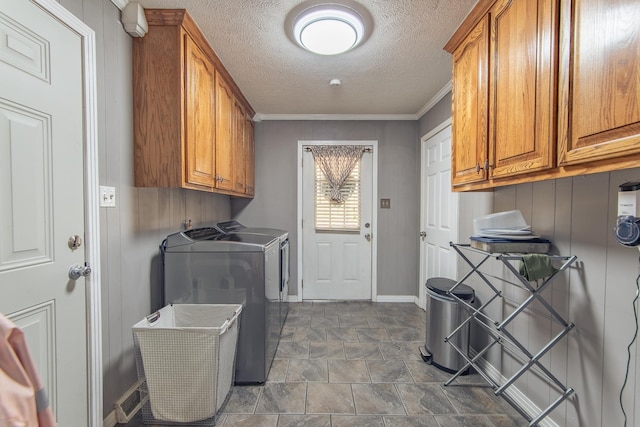 clothes washing area with baseboards, cabinet space, ornamental molding, a textured ceiling, and washer and clothes dryer