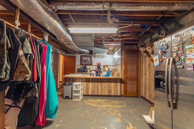 unfinished basement featuring stainless steel fridge with ice dispenser