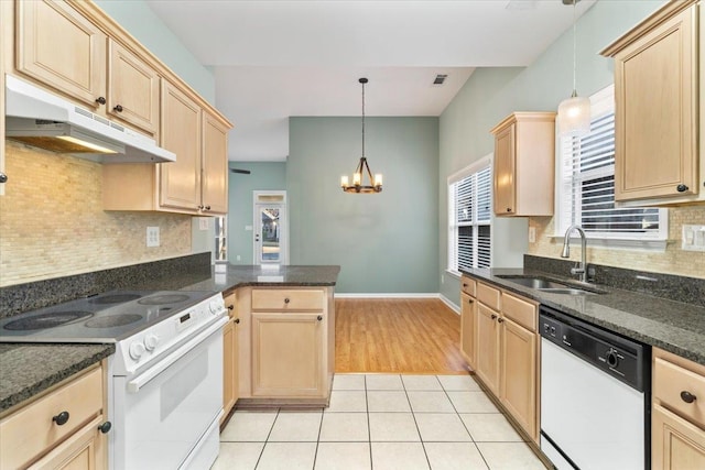 kitchen featuring white appliances, light brown cabinets, under cabinet range hood, and a sink