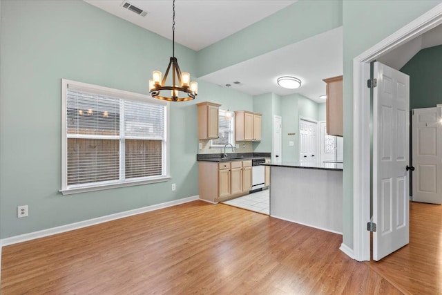 kitchen with visible vents, light brown cabinetry, a sink, dark countertops, and white dishwasher