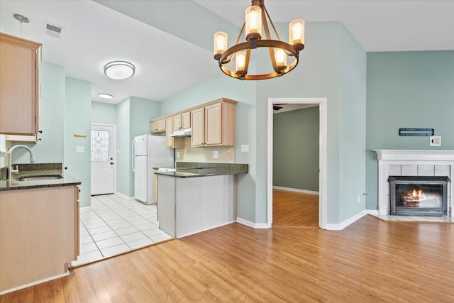 kitchen featuring visible vents, a sink, open floor plan, freestanding refrigerator, and a tile fireplace