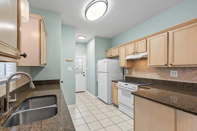 kitchen with white appliances, light brown cabinetry, decorative backsplash, a sink, and under cabinet range hood