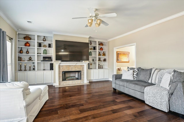 living area with ceiling fan, wood finished floors, ornamental molding, and a tile fireplace