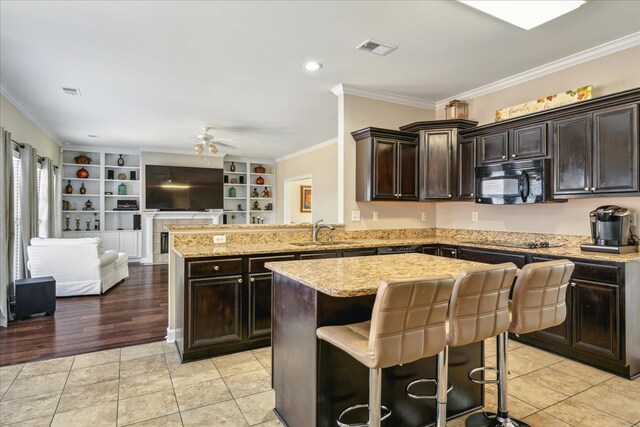 kitchen featuring visible vents, a kitchen island, black microwave, open floor plan, and a sink