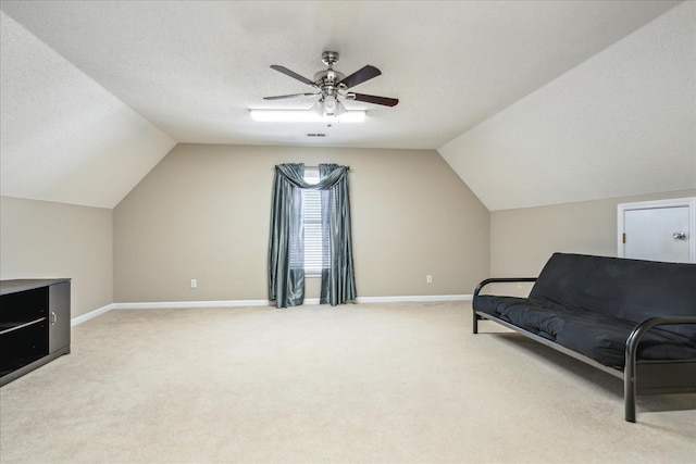 living area with light carpet, a textured ceiling, lofted ceiling, and baseboards