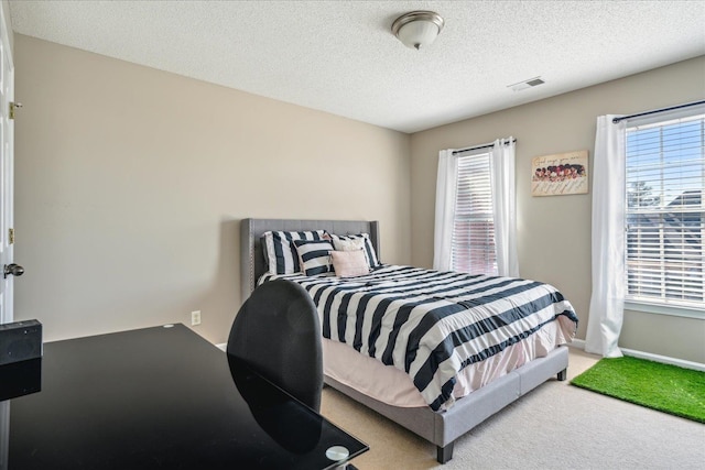 bedroom featuring visible vents, multiple windows, a textured ceiling, and carpet floors