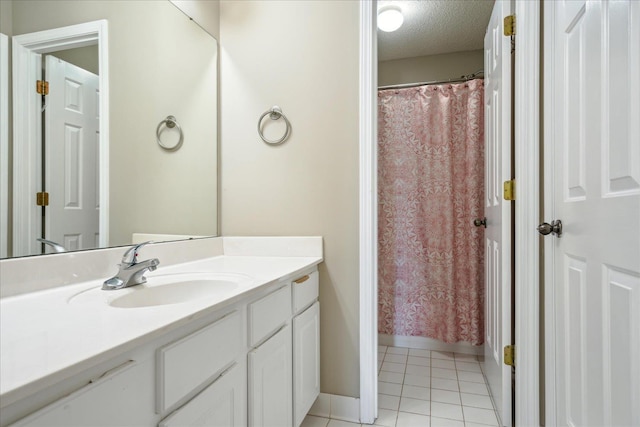 full bath featuring a shower with curtain, a textured ceiling, tile patterned flooring, baseboards, and vanity