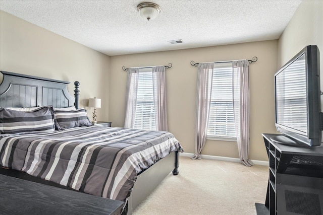 carpeted bedroom with visible vents, baseboards, and a textured ceiling