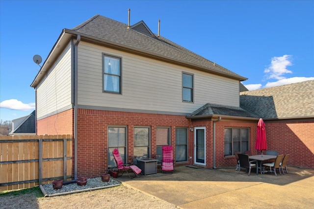 back of property featuring a patio, brick siding, roof with shingles, and fence