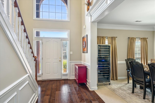 entryway featuring beverage cooler, visible vents, dark wood-style flooring, stairs, and crown molding