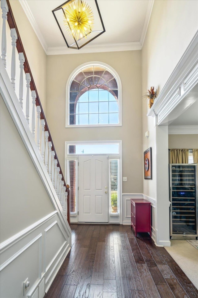 entrance foyer with wine cooler, plenty of natural light, ornamental molding, and hardwood / wood-style flooring