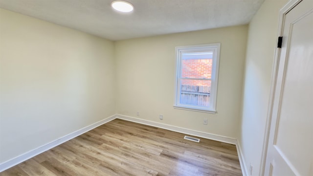 spare room with wood finished floors, baseboards, and visible vents