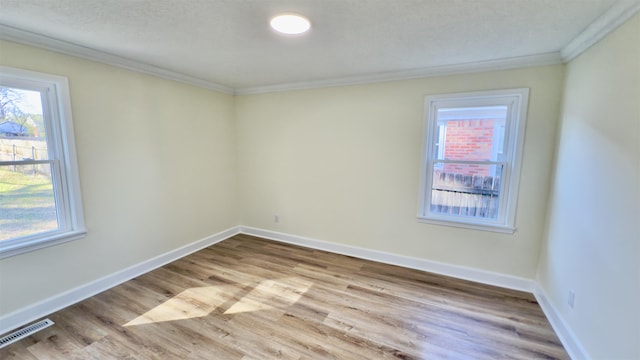 unfurnished room featuring a wealth of natural light, visible vents, baseboards, and ornamental molding