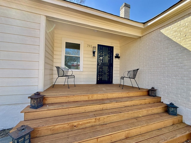 property entrance with brick siding and a chimney