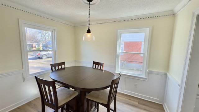 dining space featuring a wainscoted wall, a textured ceiling, and light wood finished floors