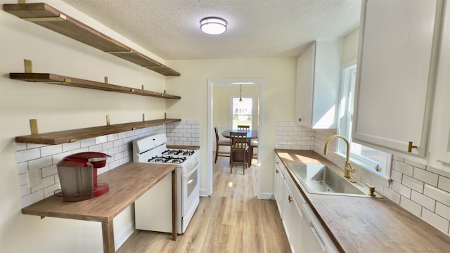 kitchen with light wood-type flooring, open shelves, a sink, white appliances, and white cabinets