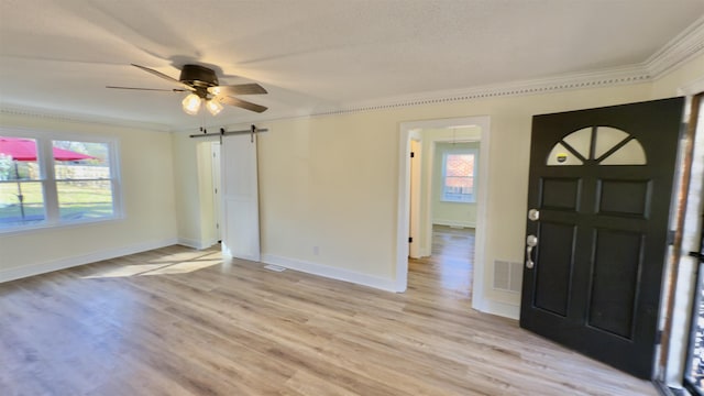 entrance foyer with light wood-type flooring, a barn door, plenty of natural light, and visible vents